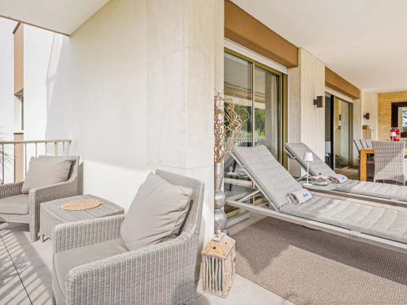 Terrace of an apartment in Cannes with sun loungers and table, unobstructed view of a park.