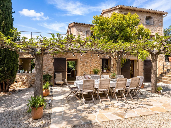 Stone villa with terrace and dining table, surrounded by greenery in Opio.