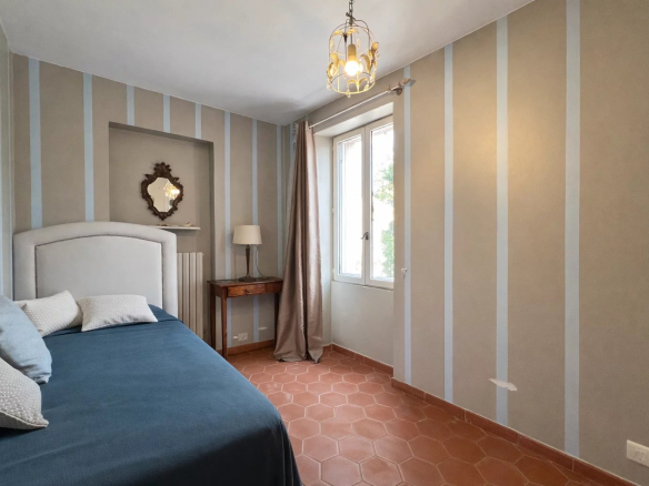 Bedroom in a villa with bed, mirror and window overlooking the outside.