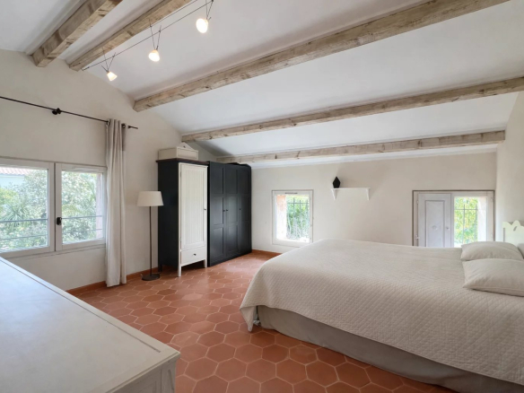 Spacious room with double bed and windows overlooking a wooded garden.