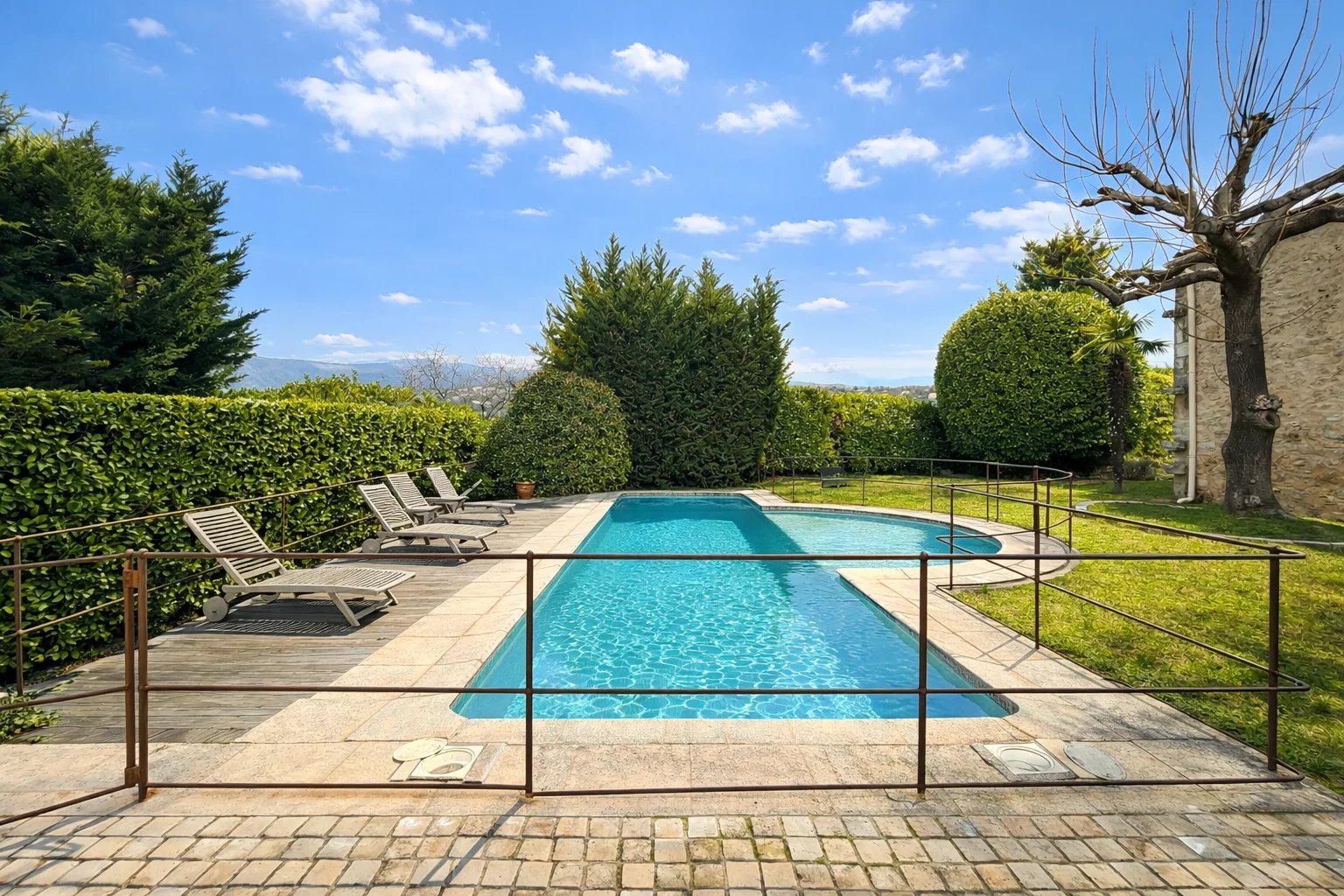 Swimming pool in the villa's garden Swimming pool surrounded by sun loungers in a green garden with hedges.