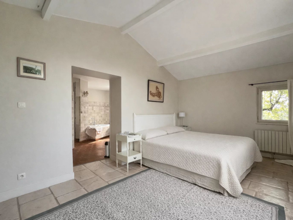 Room in a villa with double bed and access to a bathroom, simple and bright decor.