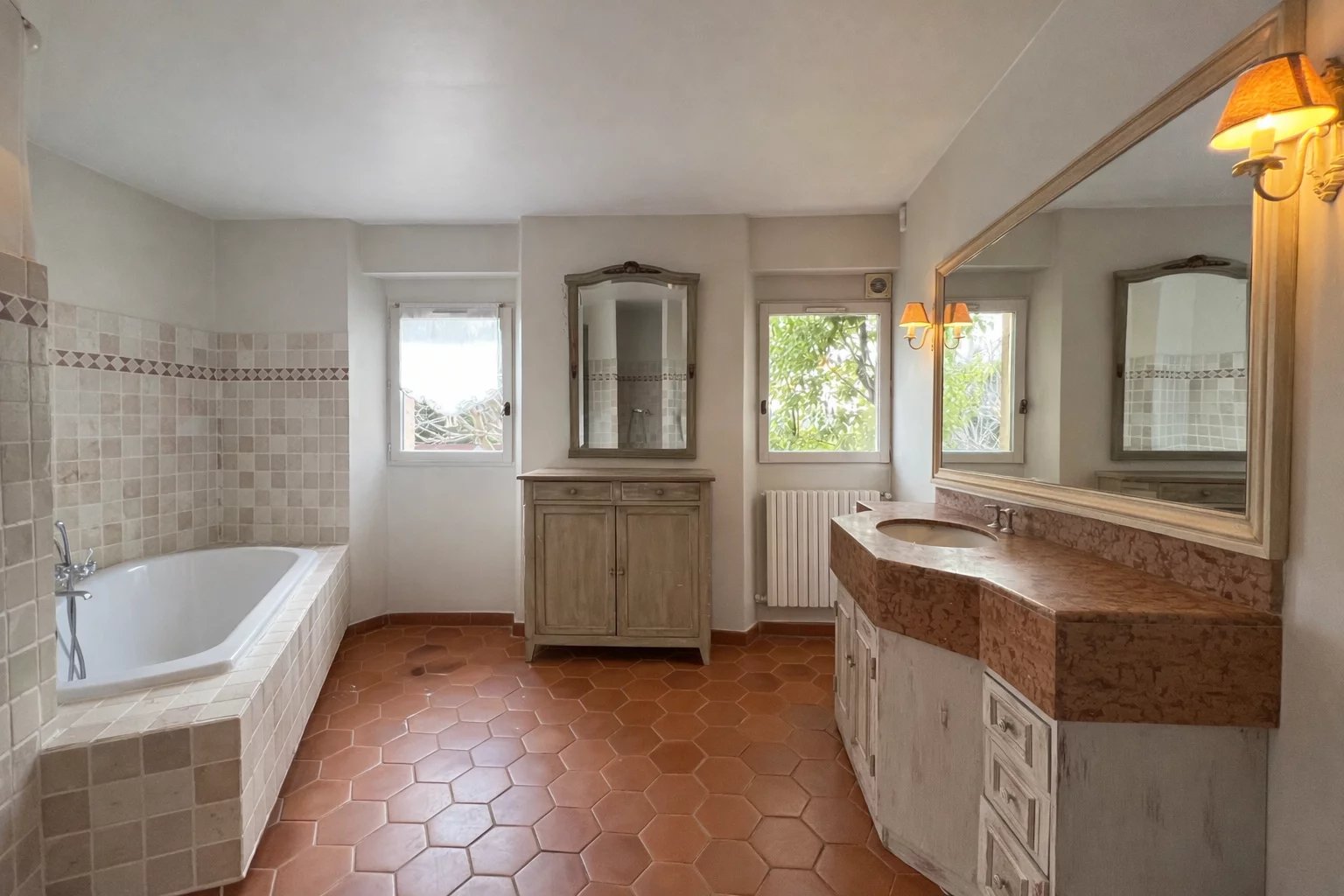 Bathroom of the villa in Opio Spacious bathroom with bathtub and sink, terracotta tiles, windows overlooking the outside.