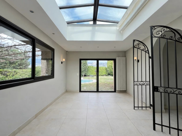 Bright interior of a villa with access to a garden, wrought iron windows and door.
