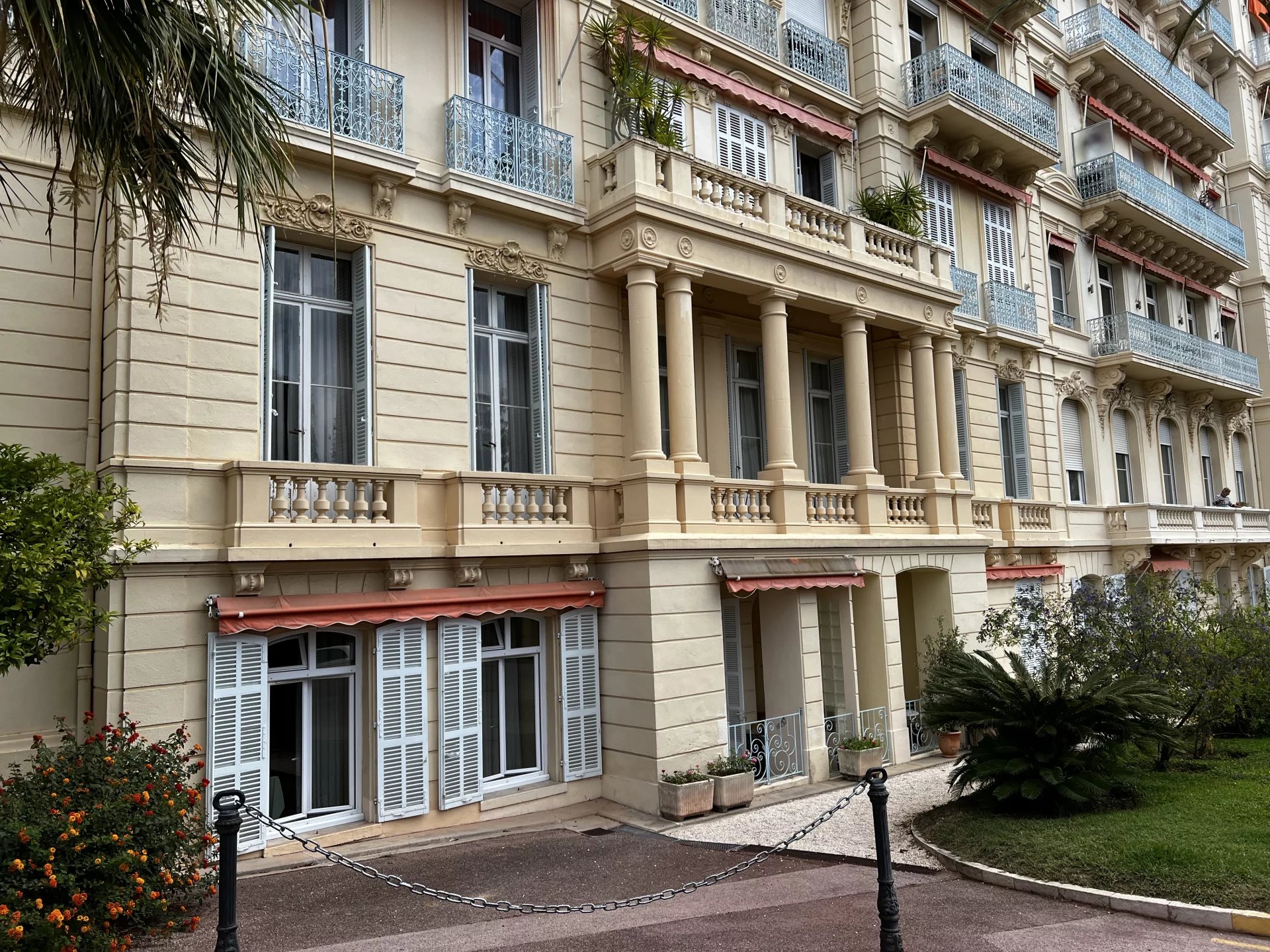 Immeuble bourgeois à Cannes Façade d'un immeuble bourgeois à Cannes avec balcons et parc arboré.
