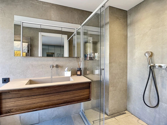 Salle de bain moderne avec douche en verre et meuble en bois, décoration contemporaine.