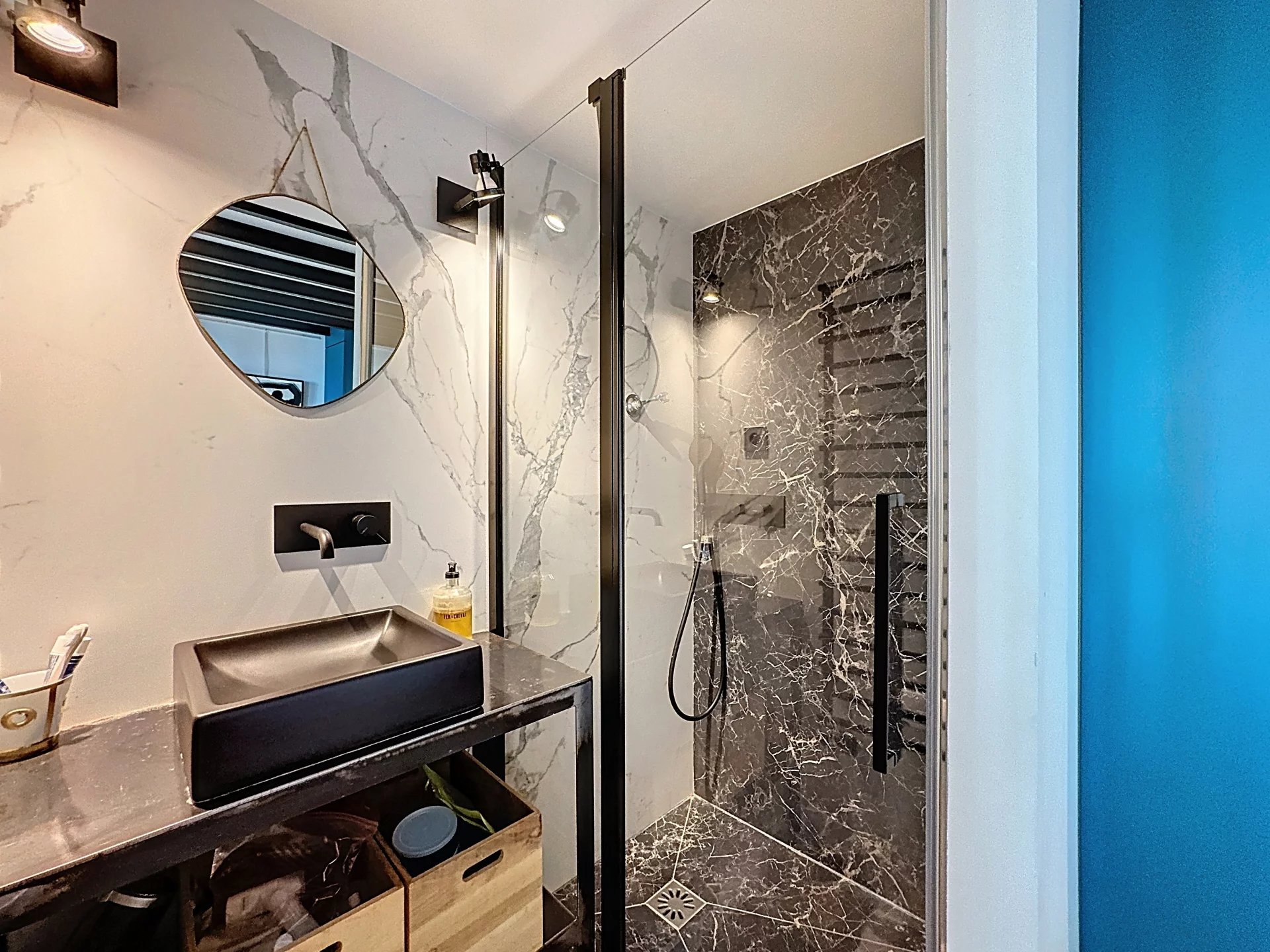 Salle de bain d’un appartement type loft Salle de bain moderne avec douche en verre et décor en marbre noir.