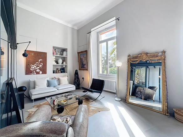 Salon d'un appartement type loft avec des meubles modernes et un grand miroir, lumière naturelle.