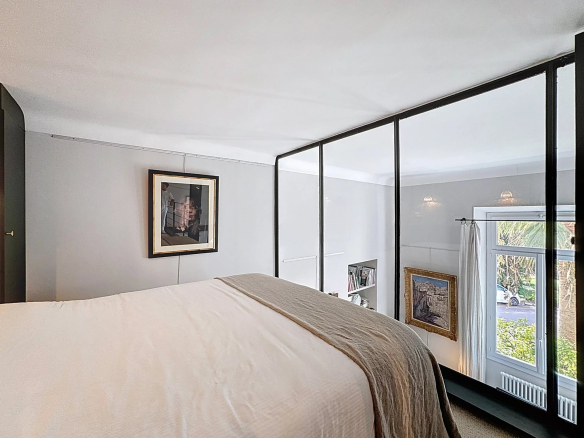 Chambre d'un appartement type loft avec vue sur l'extérieur, murs en verre et décoration moderne.