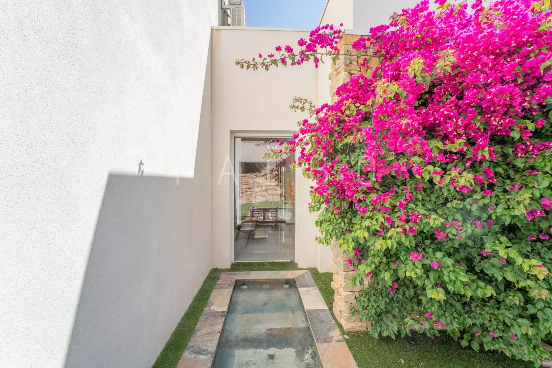 Entrance to a contemporary villa with a water feature and flowering bougainvillea in La Ciotat.