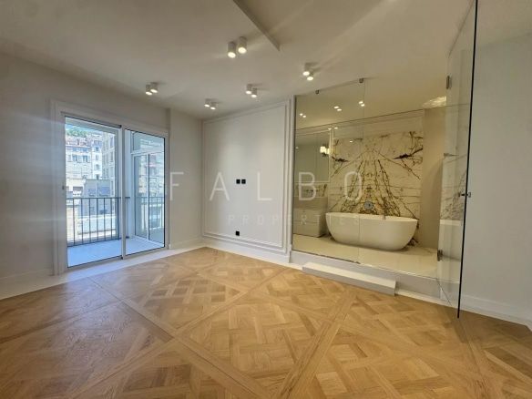 Interior of a renovated apartment with a view of the Old Port of Marseille, marble bathtub visible.