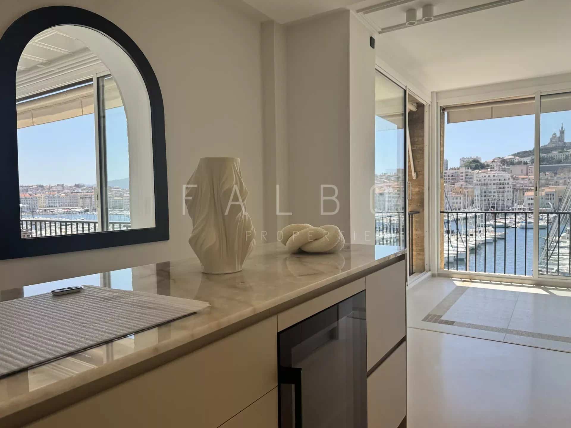 Interior of a renovated apartment overlooking the Old Port of Marseille, including a mirror and a modern piece of furniture.