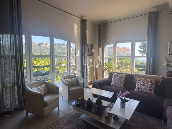 Intérieur d'une villa avec vue sur la mer et les collines de Cassis, salon lumineux et confortable.