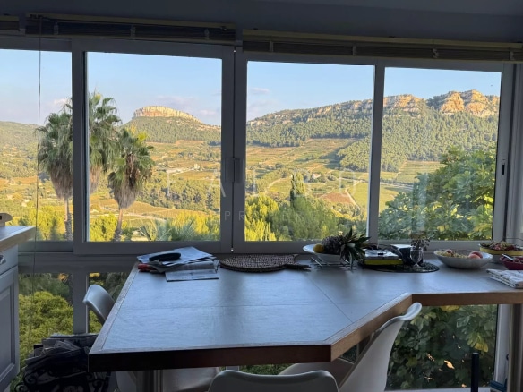 Vue depuis une villa à Cassis avec une table, des collines et des vignes en arrière-plan.