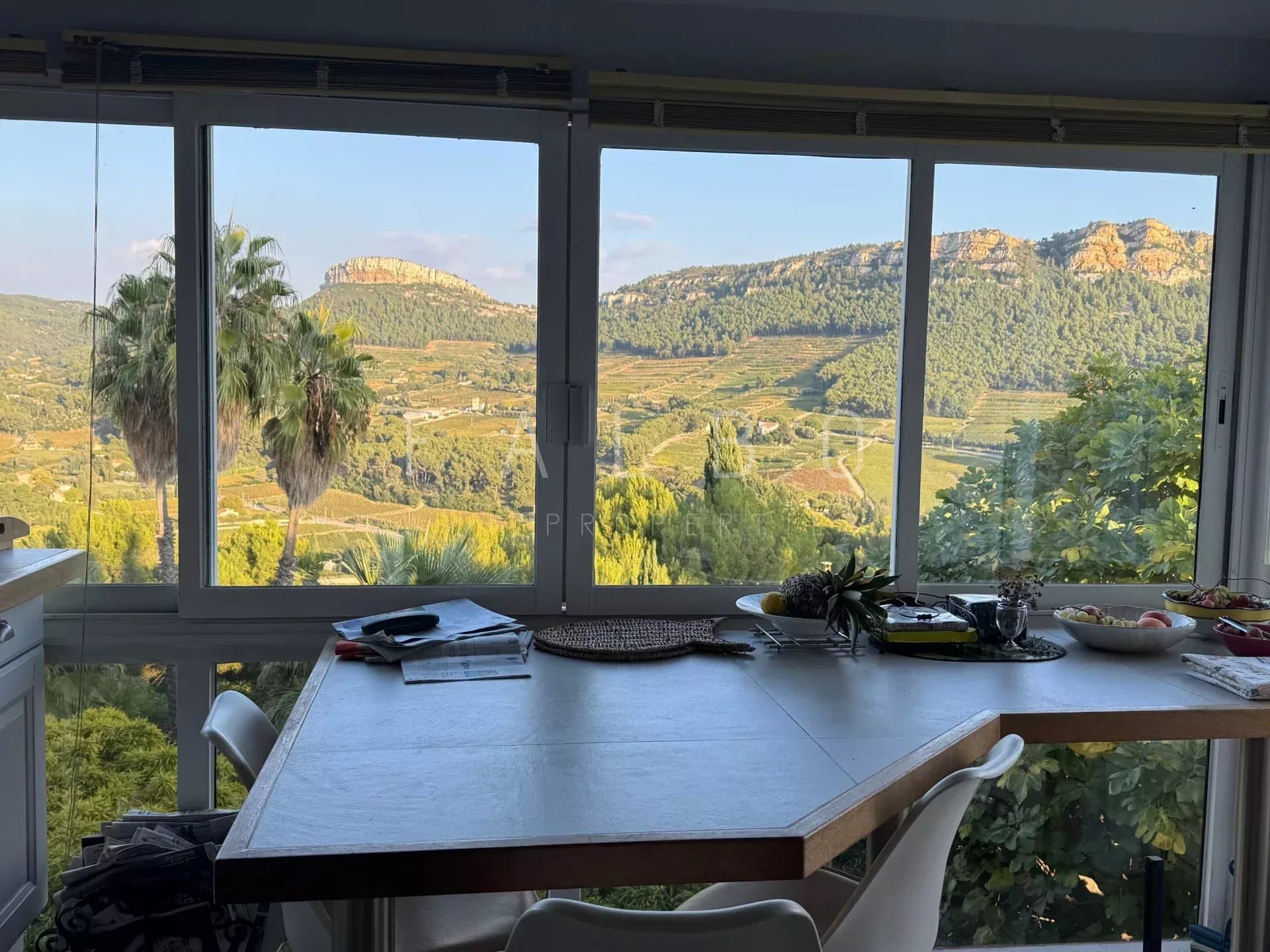 Vue depuis une villa à Cassis avec une table, des collines et des vignes en arrière-plan.