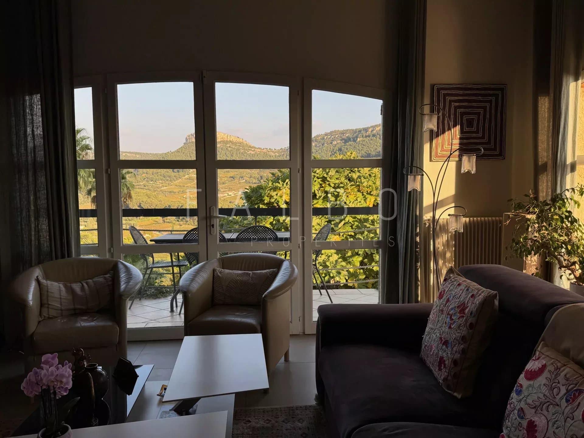 Intérieur d'une villa avec vue sur la mer et les collines, mobilier confortable.