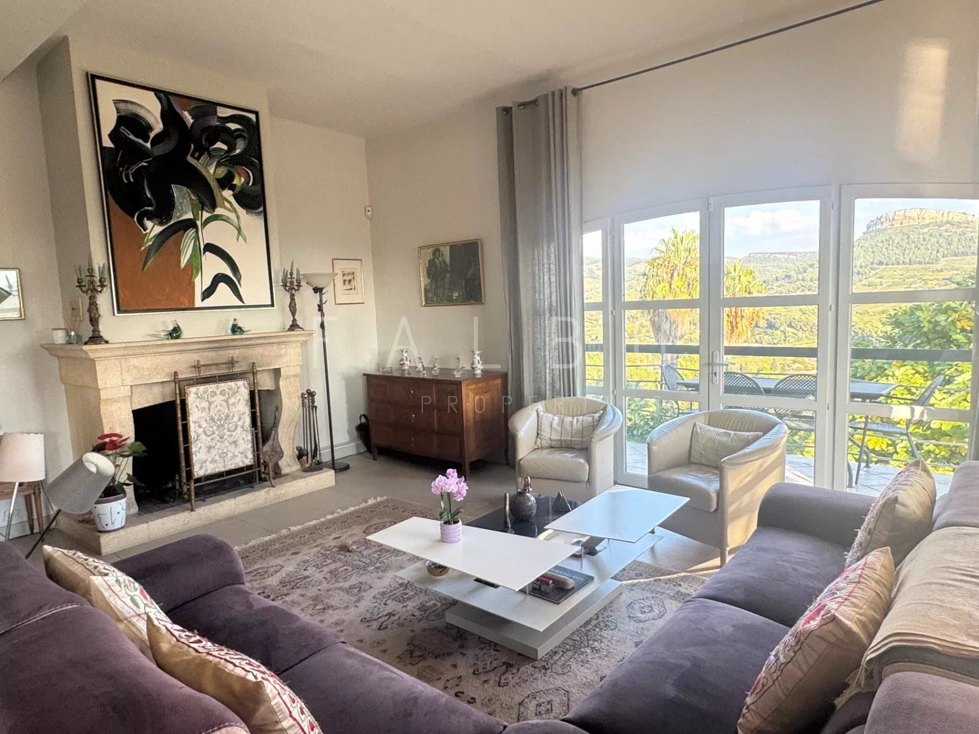 Intérieur d'une villa avec salon lumineux, cheminée et vue sur la nature.