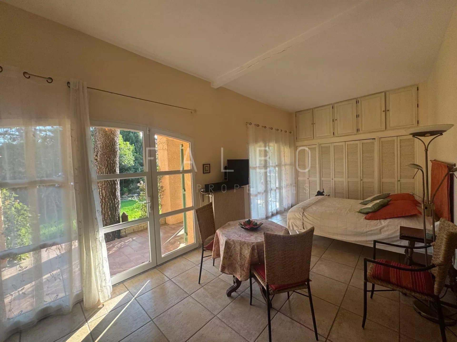 Chambre lumineuse avec table et chaises, accès à un jardin dans une villa à Cassis.
