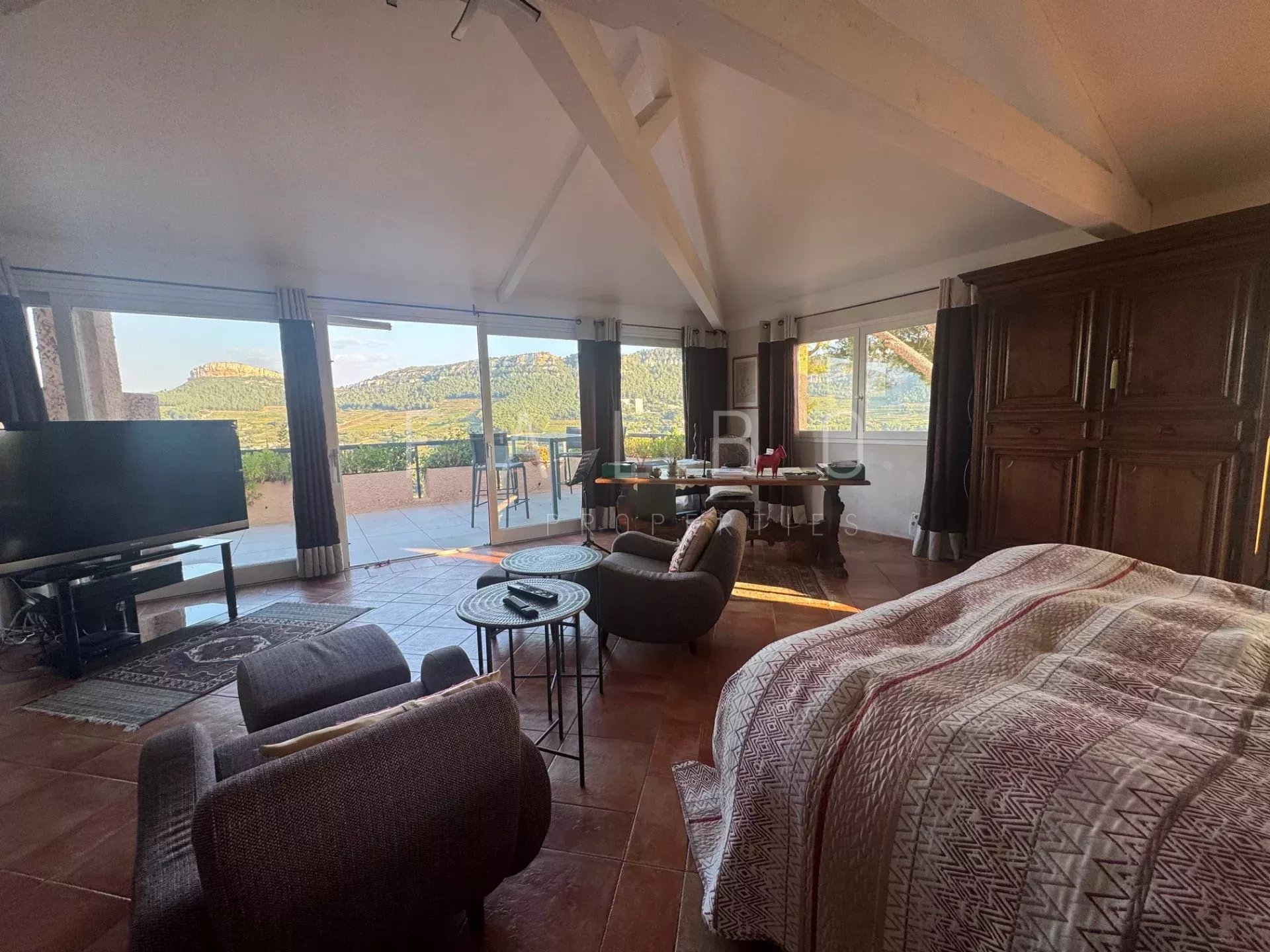 Intérieur d'une villa avec vue sur la mer et les collines, mobilier moderne et lumineux.