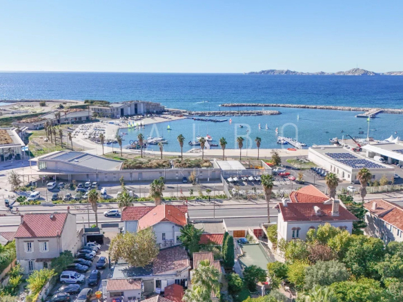 Vue aérienne de la Corniche Kennedy à Marseille 8e, montrant des maisons et le port.