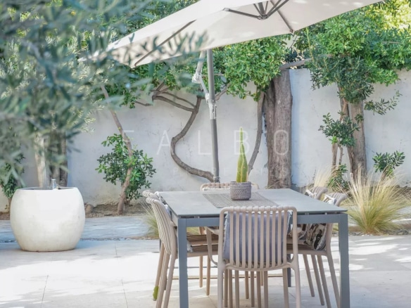 Terrasse d'une villa contemporaine avec table et chaises sous un parasol, jardin paysager à Marseille 8e.