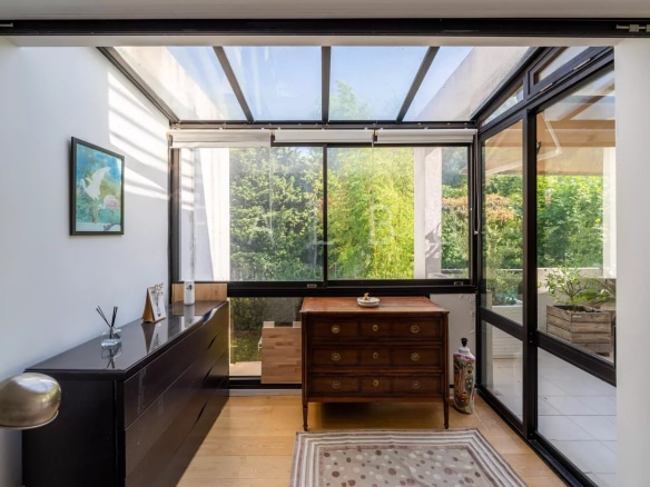 Intérieur d'un appartement avec véranda, meuble en bois et vue sur la verdure à Marseille 8e.
