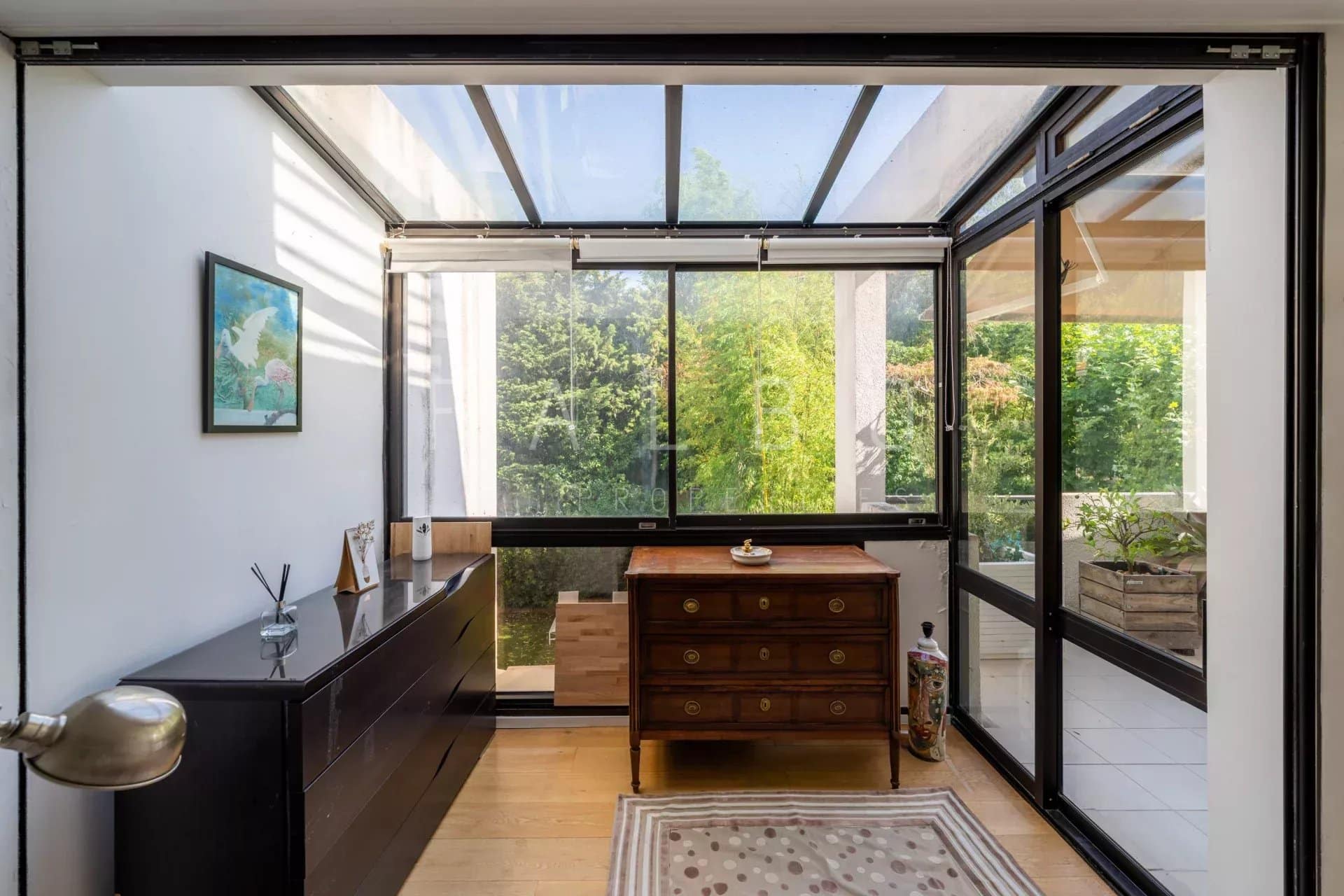 Intérieur d'un appartement avec véranda, meuble en bois et vue sur la verdure à Marseille 8e.