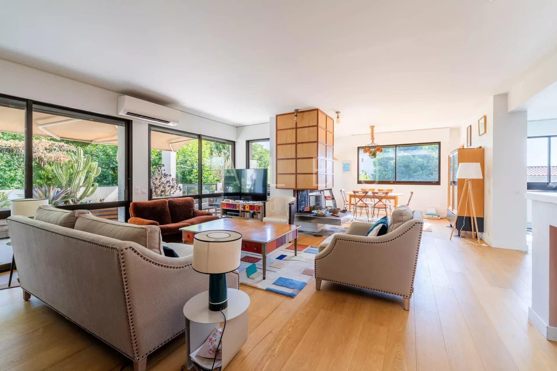 Intérieur d'un appartement moderne avec salon spacieux, cuisine et salle à manger, baigné de lumière.