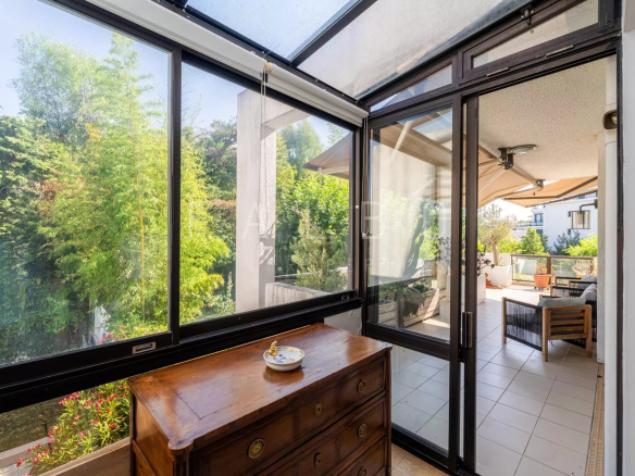 Vue intérieure d'un appartement avec grandes fenêtres donnant sur une terrasse verdoyante à Marseille 8e.