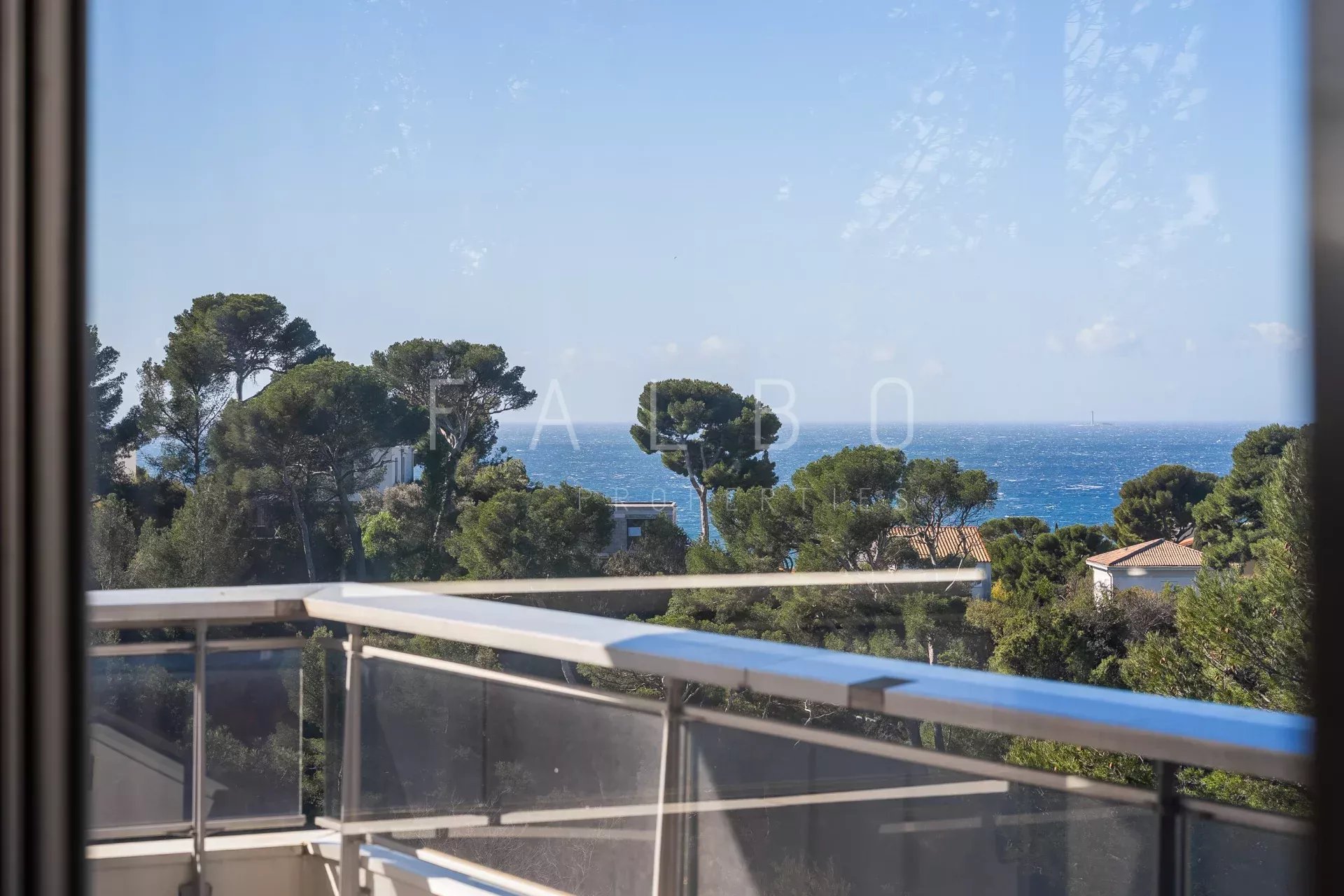 Vue mer depuis une terrasse d'appartement à Marseille 8e, entourée de pins.