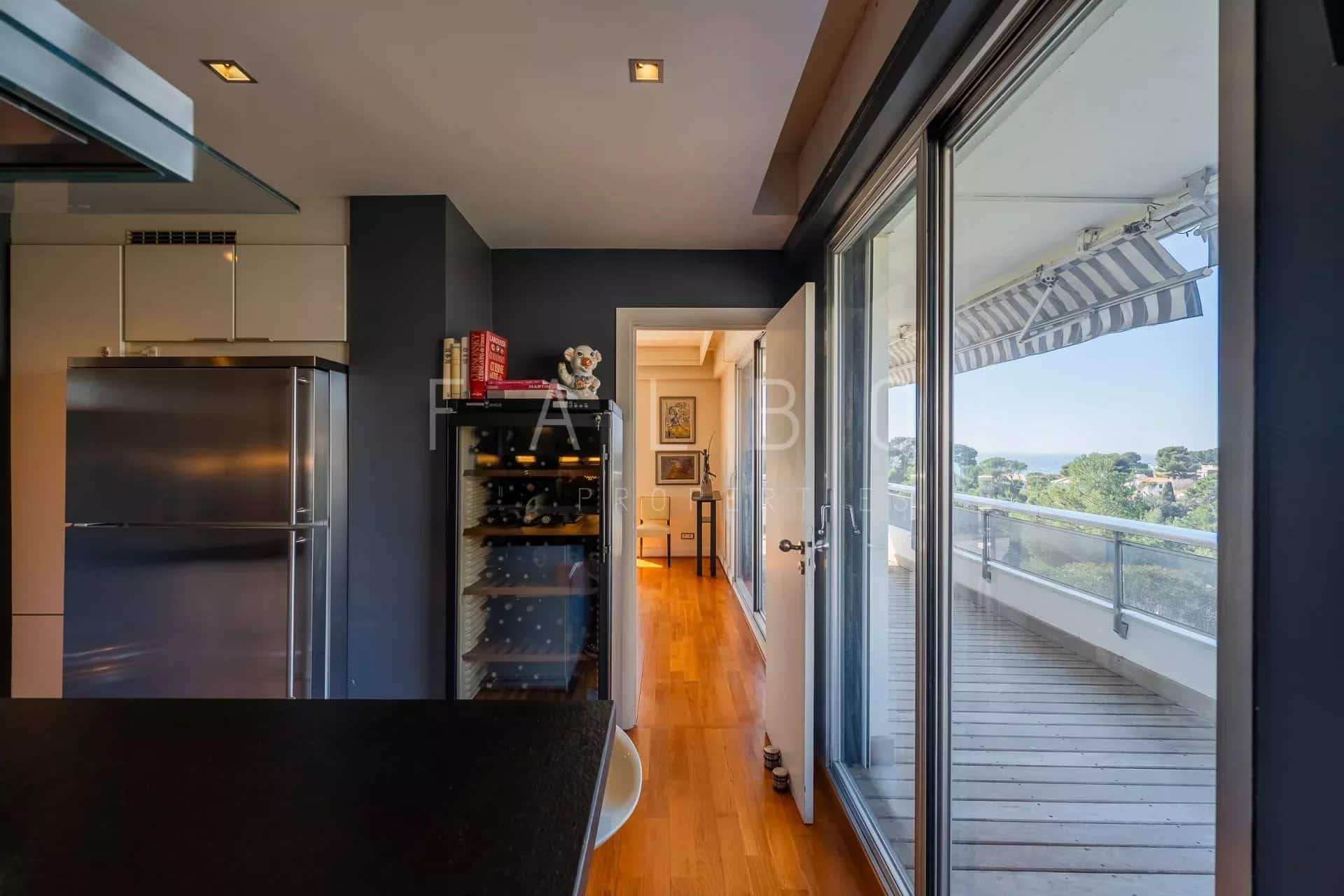 Intérieur d'un appartement avec cuisine ouverte et accès à une terrasse, vue sur la mer à Marseille.