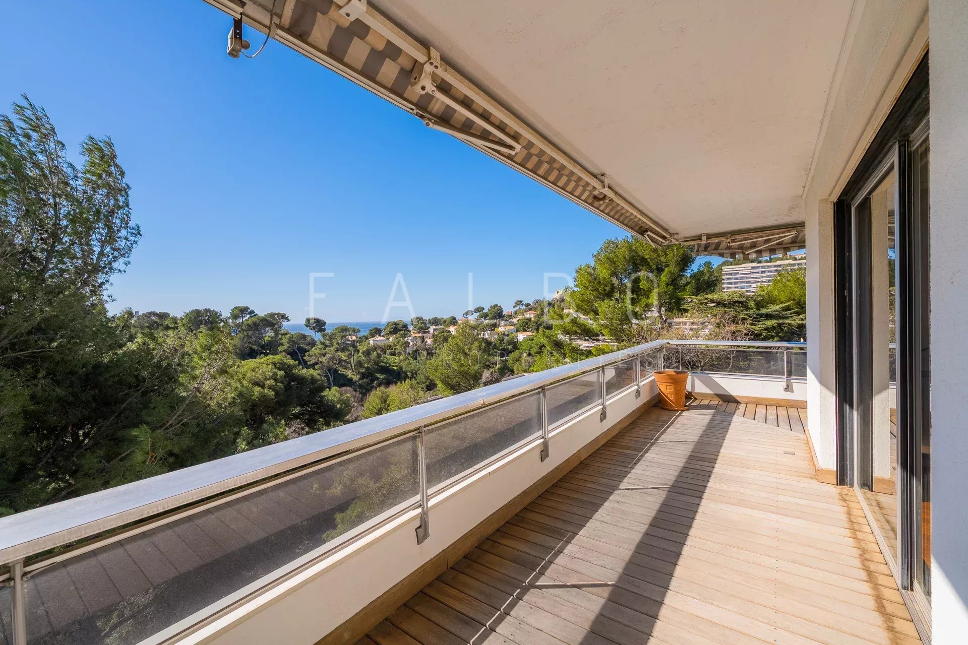 Terrasse d'un appartement avec vue sur la mer à Marseille, entourée de pins.