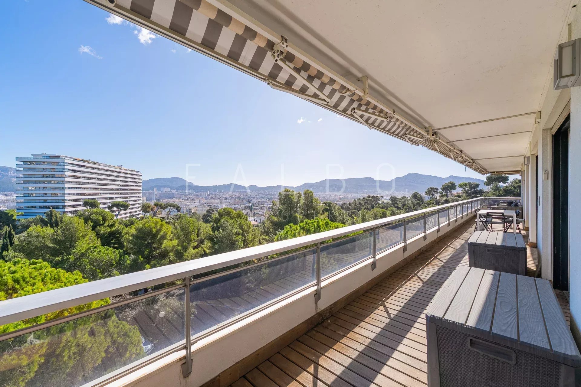 Terrasse d'un appartement avec vue sur la mer à Marseille, entourée de pins.
