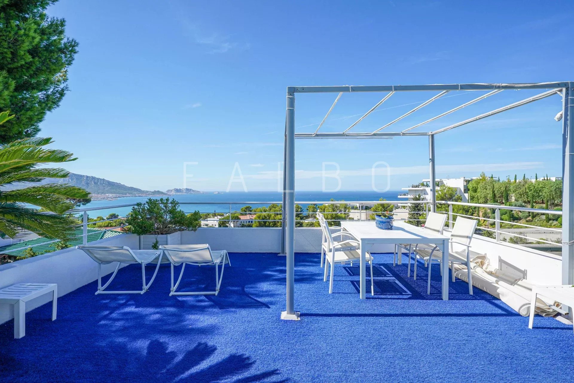 Terrace of a contemporary villa with sea view in Marseille, white outdoor furniture on a blue carpet.