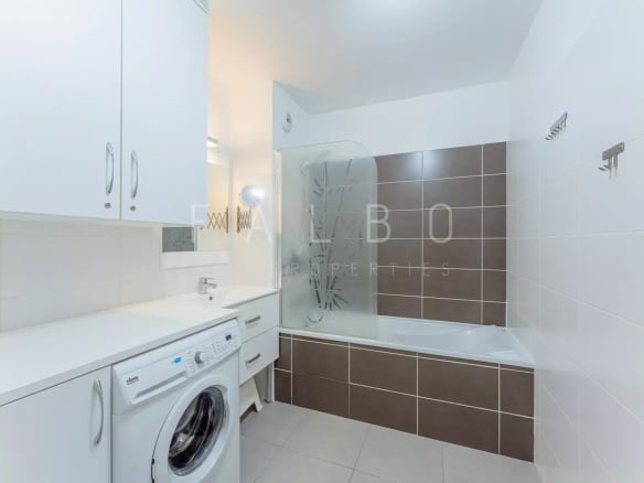 Salle de bain moderne avec baignoire et machine à laver.