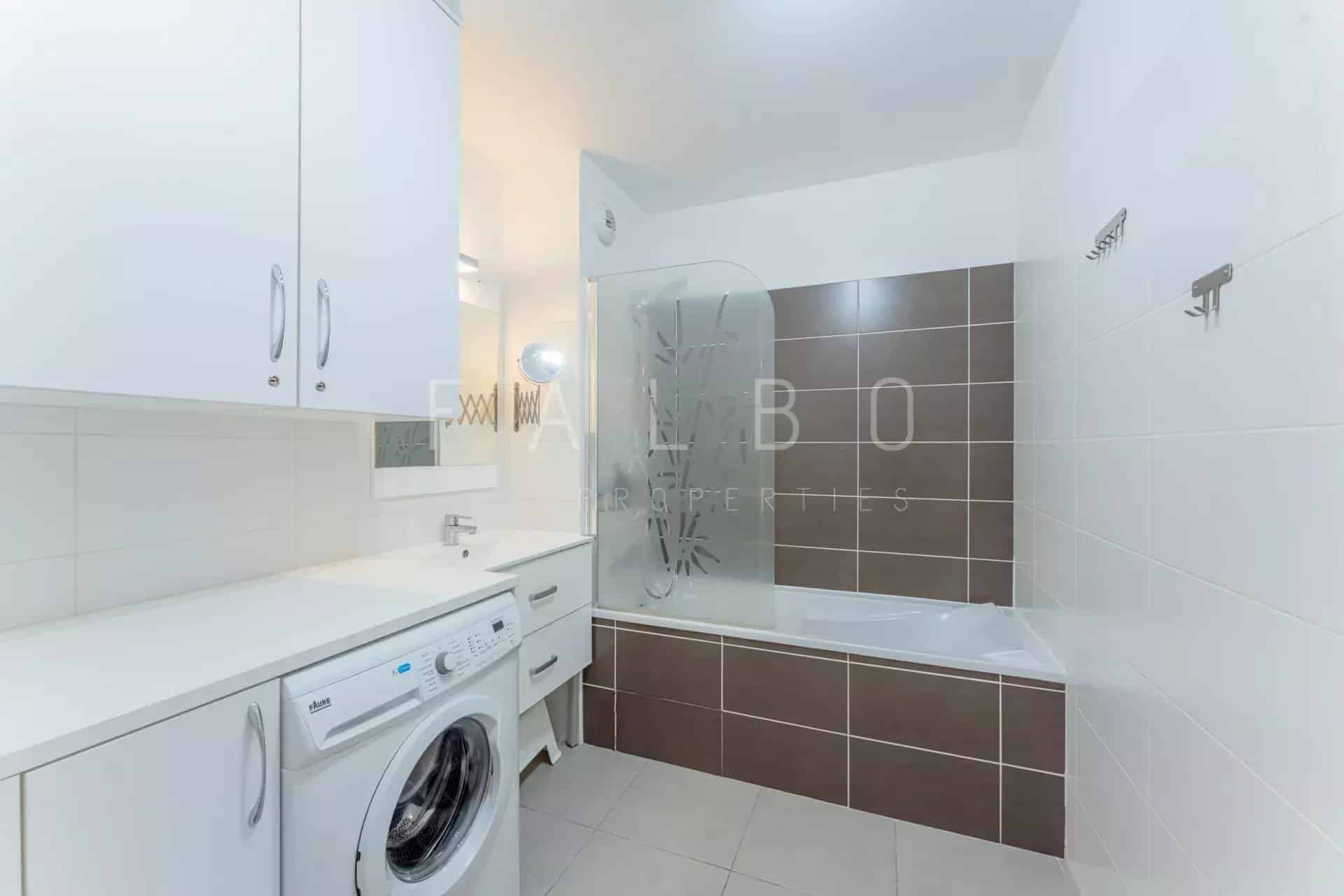 Salle de bain d’un appartement à La Ciotat Salle de bain moderne avec baignoire et machine à laver.