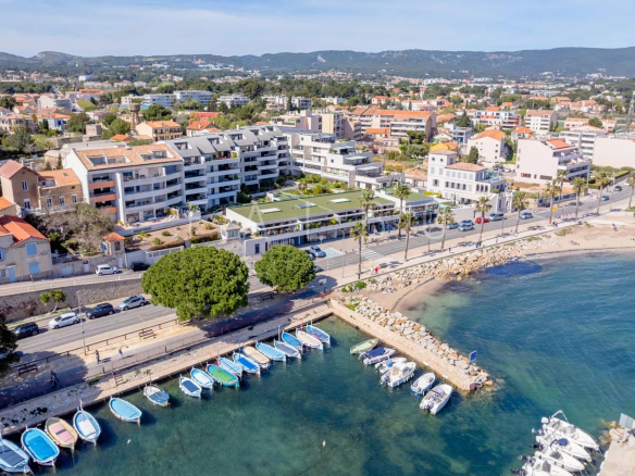 Vue aérienne d'un appartement en front de mer à La Ciotat avec accès à la plage et bateaux au port.