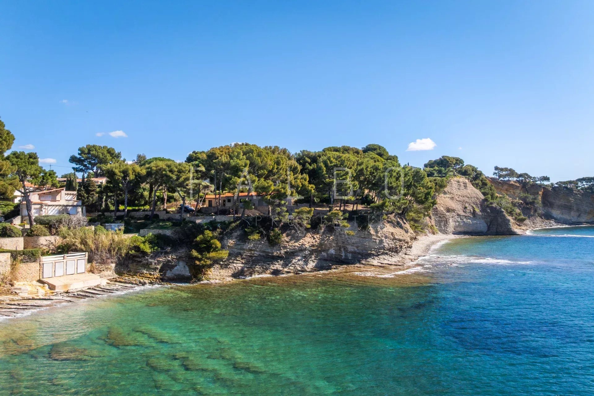 Vue de la mer et des côtes rocheuses à La Ciotat, avec des arbres et des villas en arrière-plan.
