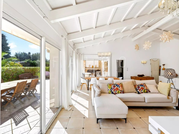 Interior of a villa with a bright living room, sofa and bay windows opening onto the terrace.