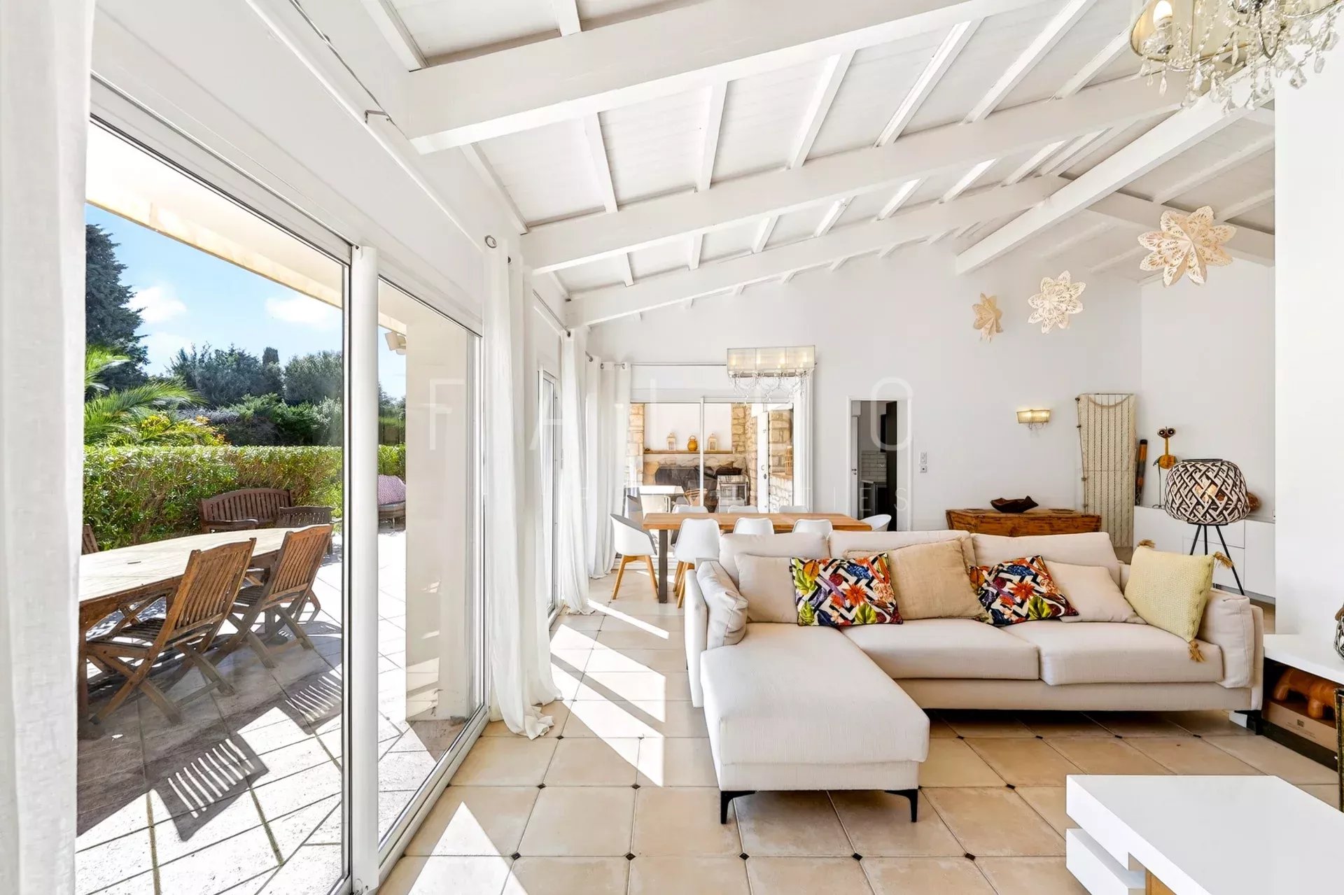 Interior of a villa with a bright living room, sofa and bay windows opening onto the terrace.