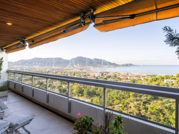 Vue panoramique sur la mer depuis un toit-terrasse à Marseille 8e, avec des montagnes en arrière-plan.