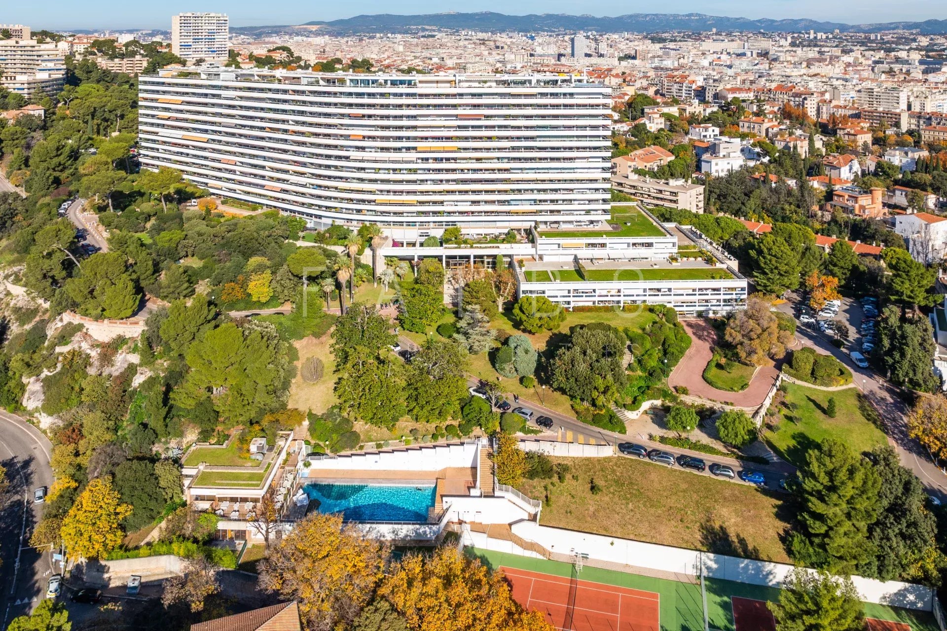 Appartement dernier étage avec vue mer à Marseille 8e Vue panoramique d'un appartement au dernier étage avec toit-terrasse à Marseille 8e, entouré de végétation méditerranéenne.