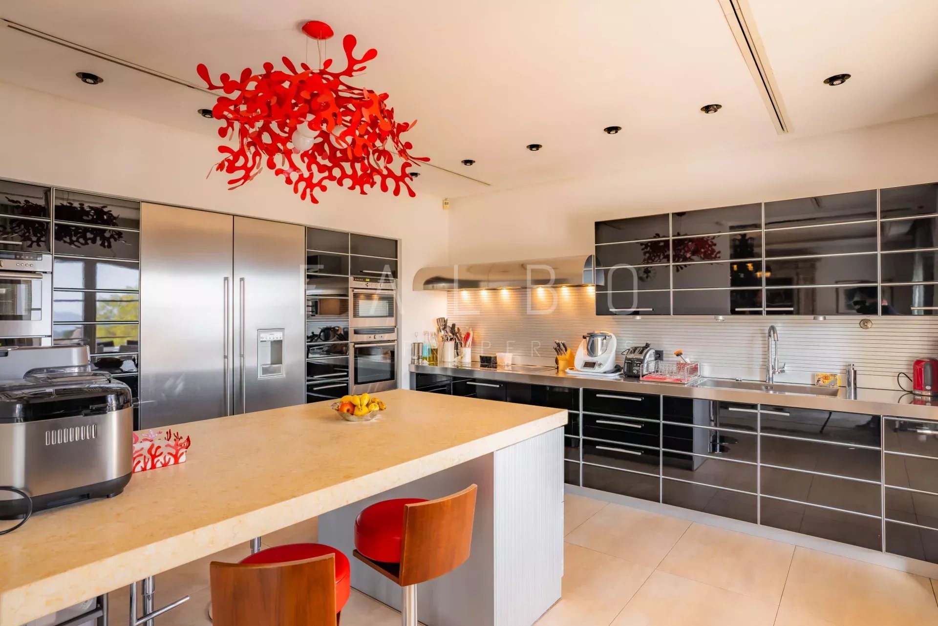 Cuisine moderne avec îlot central et équipements en acier inoxydable dans une villa contemporaine.