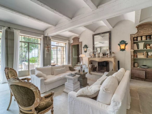 Interior of a Provençal farmhouse with a large, bright living room and a fireplace.