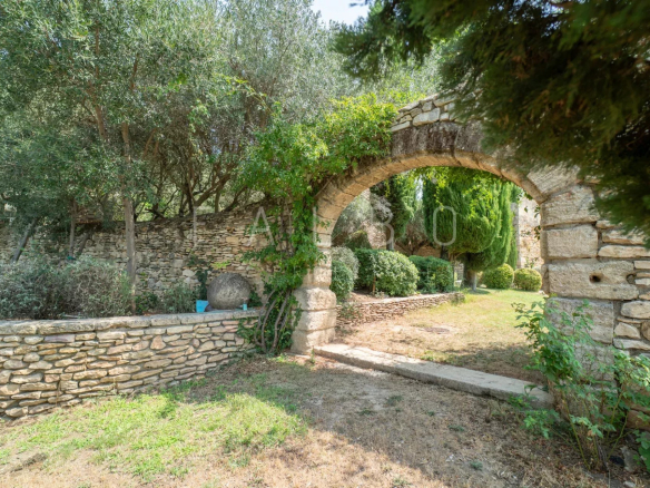 Entrance to a landscaped garden with a stone arch, 400m² farmhouse in Saint-Maximin near Uzès.