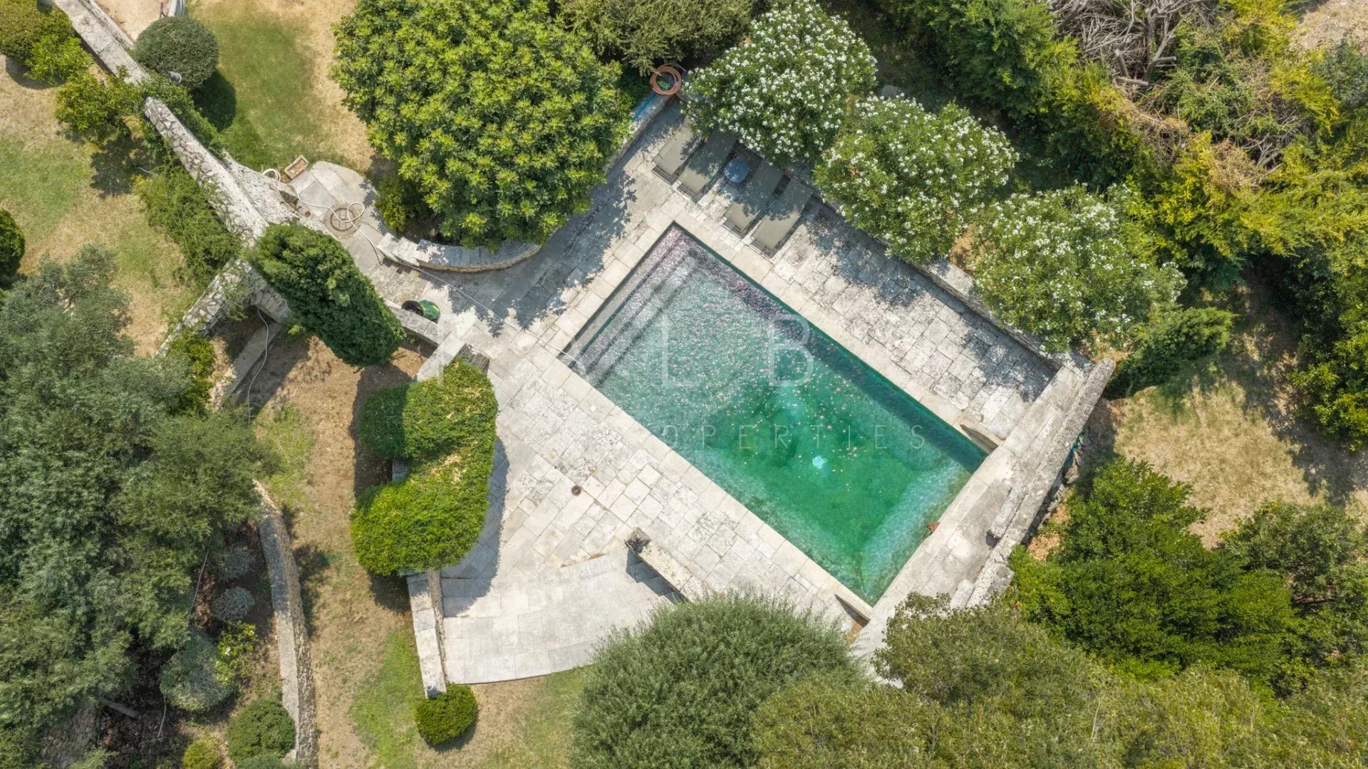 Swimming pool and gardens of the stone farmhouse Aerial view of a swimming pool surrounded by landscaped gardens in a stone farmhouse.