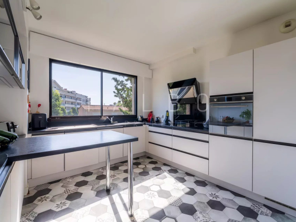 Cuisine moderne avec fenêtres et vue sur l'extérieur, carrelage noir et blanc.