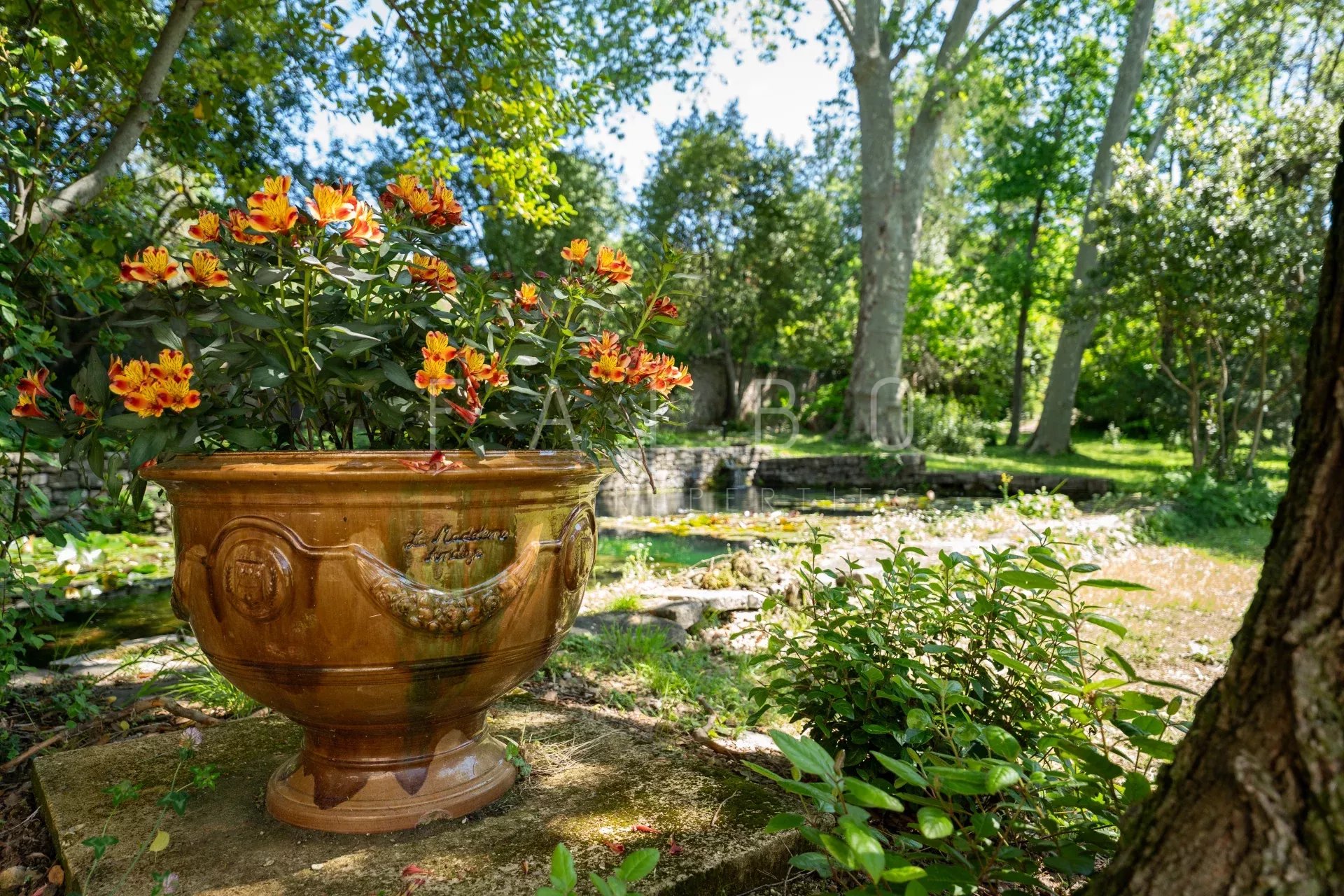 Jardin du château restauré près d’Anduze Vase en terre cuite avec des fleurs dans un jardin verdoyant près d'un château restauré.