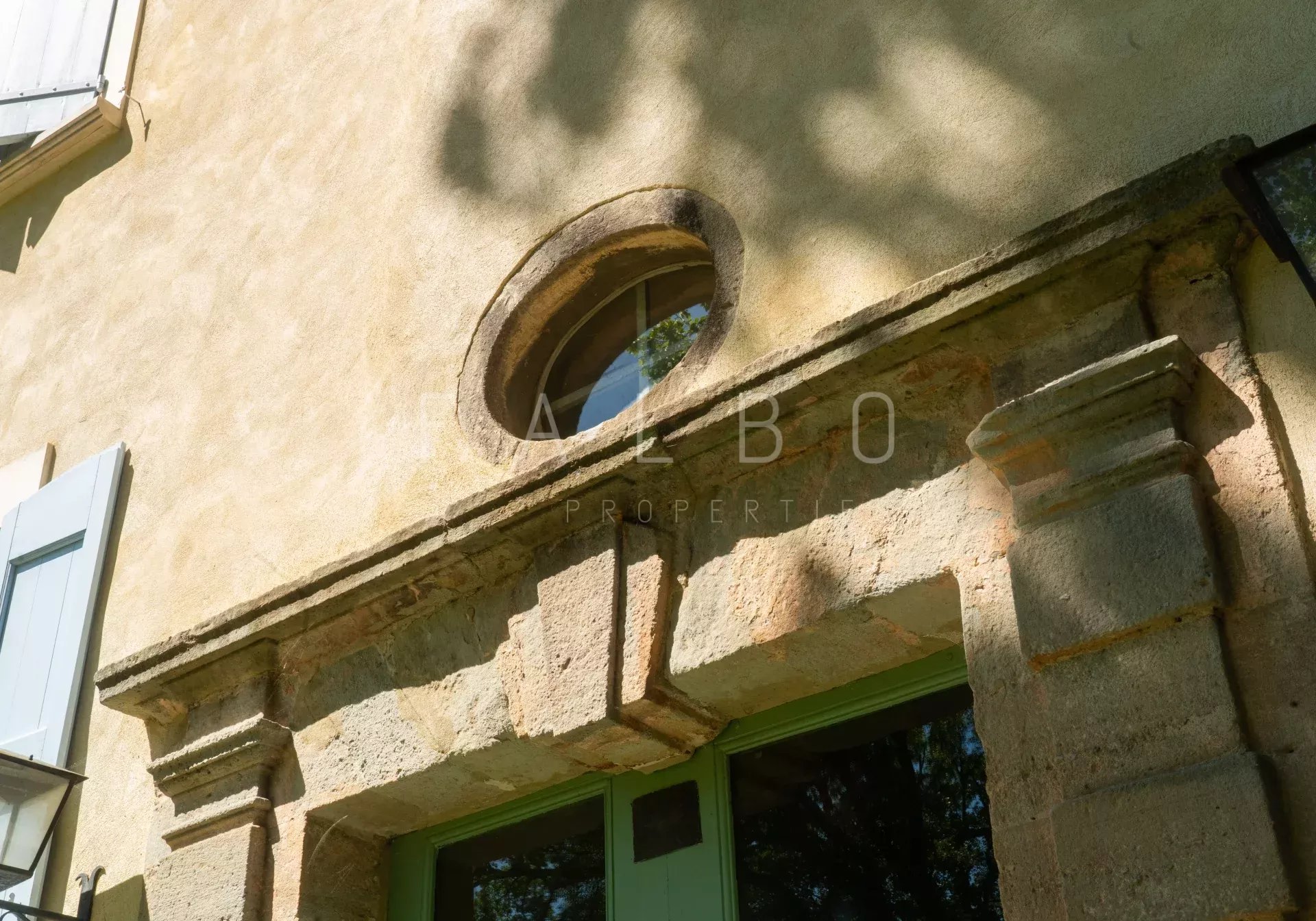 Détail de la façade d’un château près d’Anduze Détail architectural d'une façade de château restauré près d'Anduze, mettant en valeur une fenêtre circulaire.