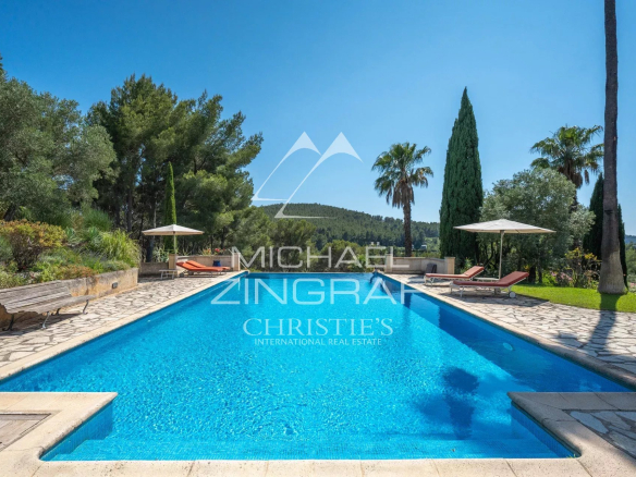 Luxurious rectangular pool with stone deck, lounge chairs and umbrellas under a bright blue sky.